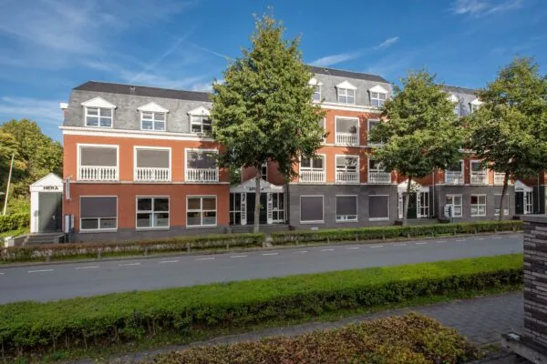 Appartementengebouw aan de Laan van Vredenoord met rode bakstenen gevel, witte balkonhekken en groene bomen langs de straat.